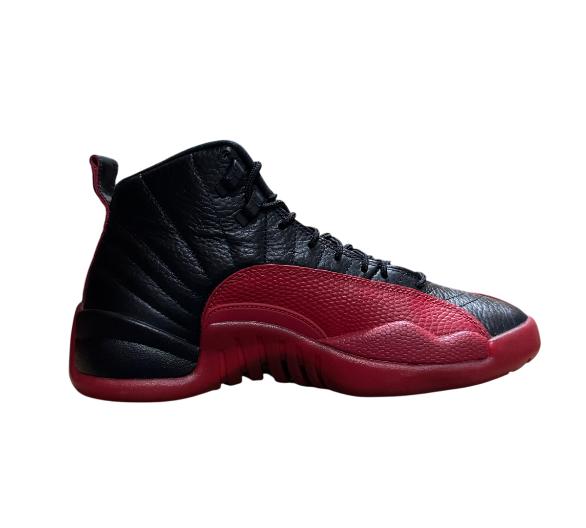 Genesis Boutique Jordan 12 Flu Game sneakers in black and red leather with textured mudguard, side profile view.