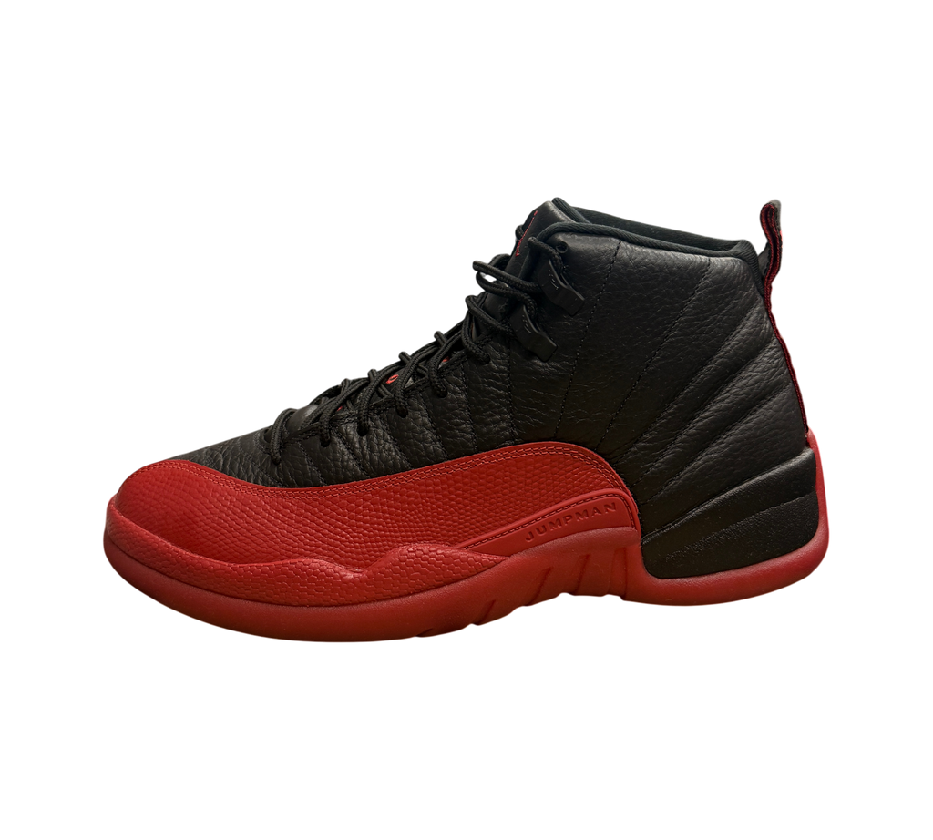 Genesis Boutique Jordan 12 Flu Game sneakers in black and red leather, displayed on a Nike shoebox in a retail store.