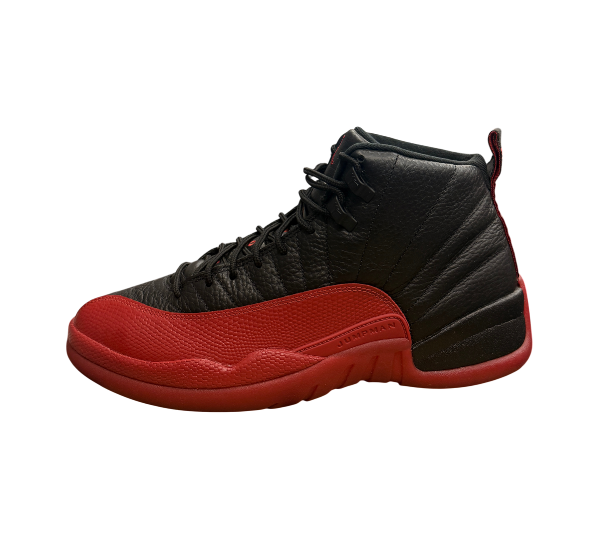 Genesis Boutique Jordan 12 Flu Game sneakers in black and red leather, displayed on a Nike shoebox in a retail store.