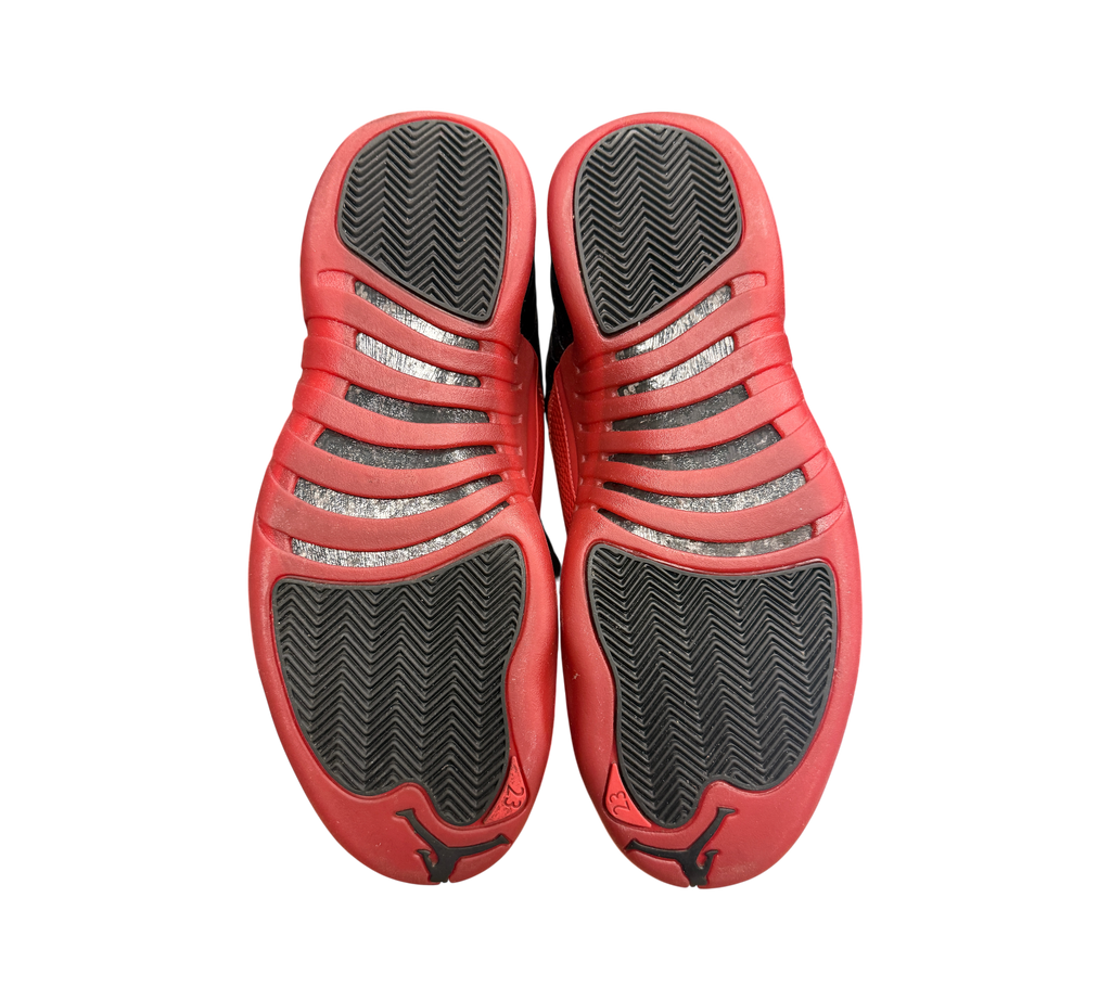 Genesis Boutique used Jordan 12 Flu Game sneakers showing the red and black herringbone traction outsoles.