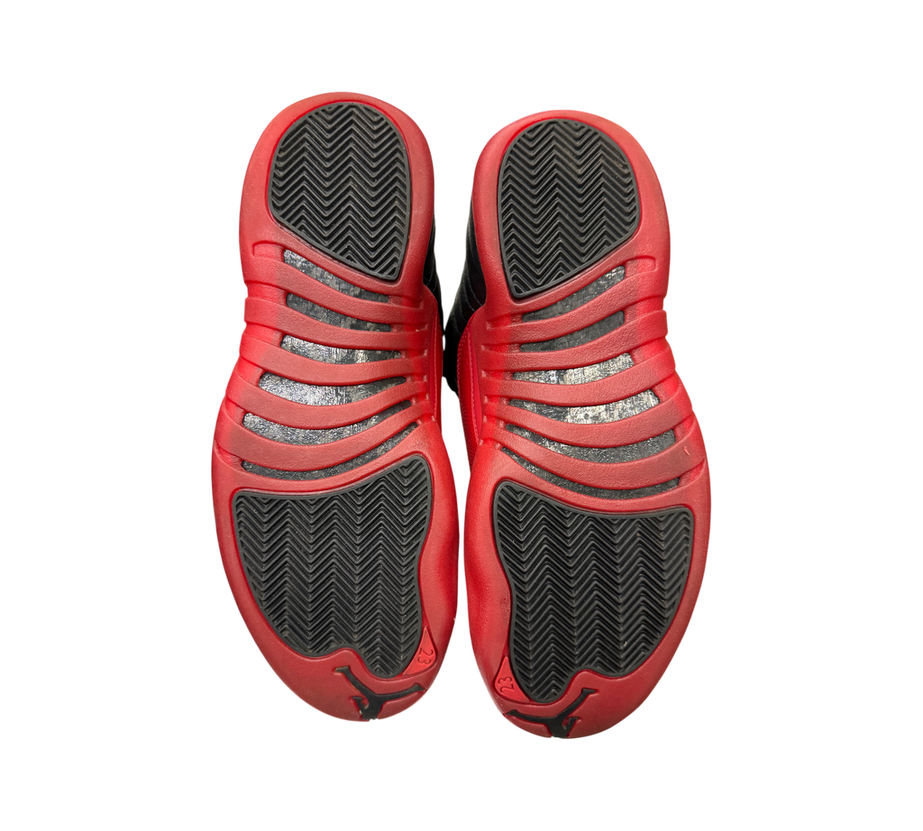 Genesis Boutique Jordan 12 Flu Game 2025 sneakers showing black and red rubber outsoles with herringbone traction
