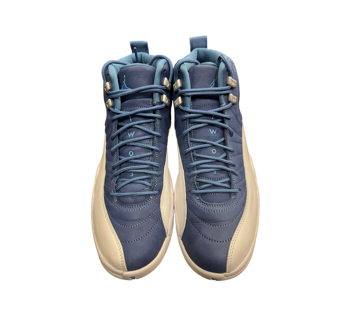Genesis Boutique Jordan 12 Indigo sneakers in blue and white leather with silver eyelets, front view.