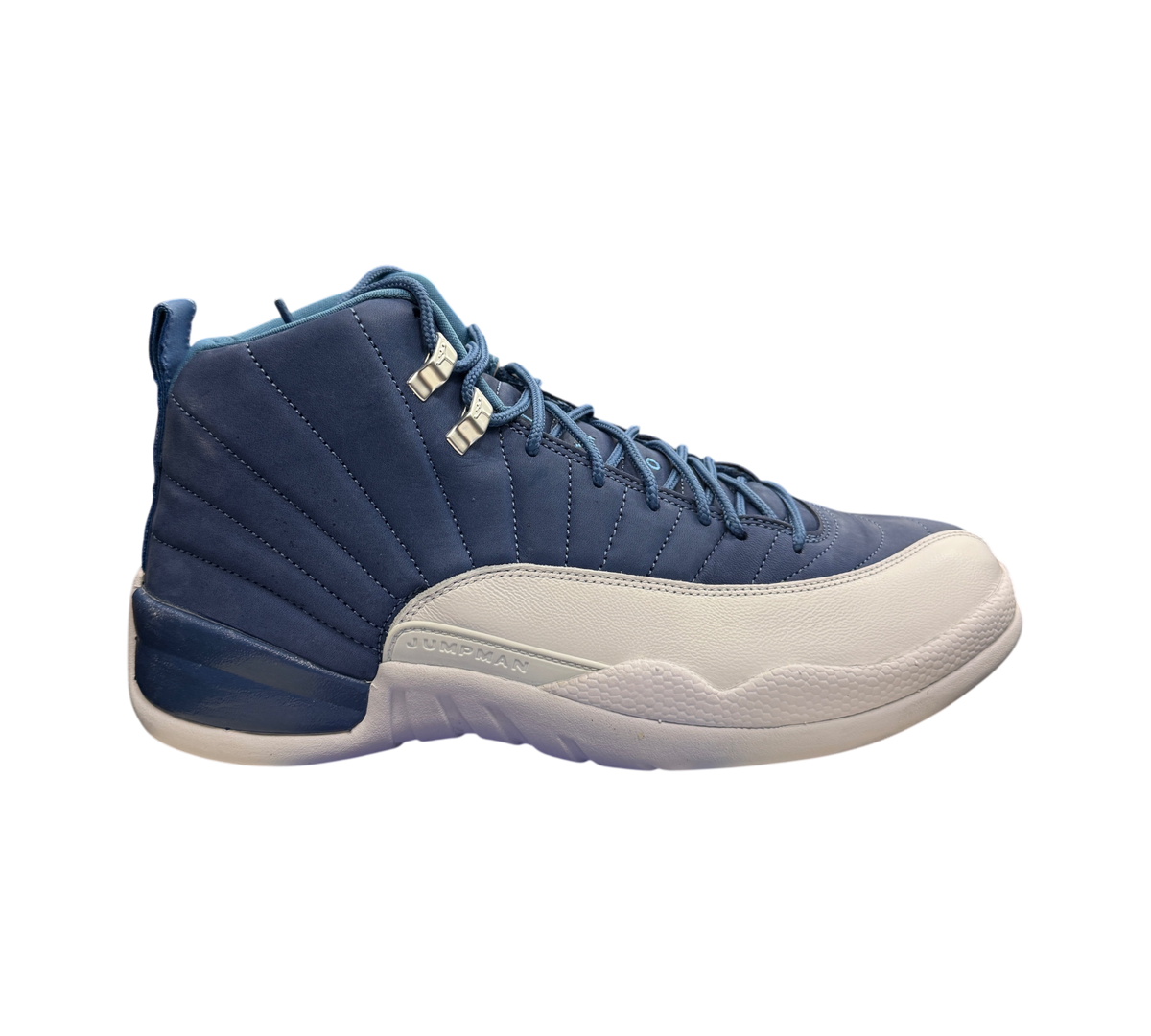 Genesis Boutique Jordan 12 Indigo sneakers featuring a blue leather upper and white textured mudguard side profile