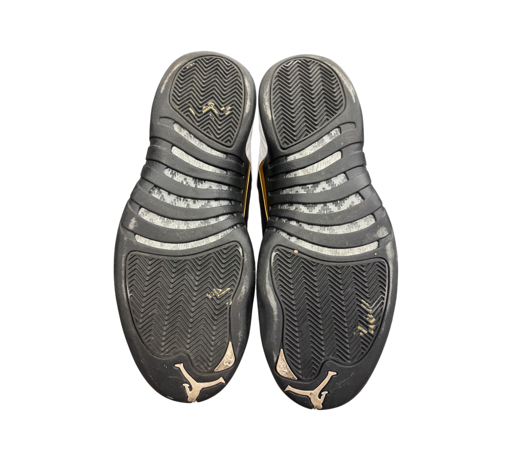 Genesis Boutique Jordan 12 Royalty Taxi sneakers showing the black rubber outsoles with herringbone traction pattern