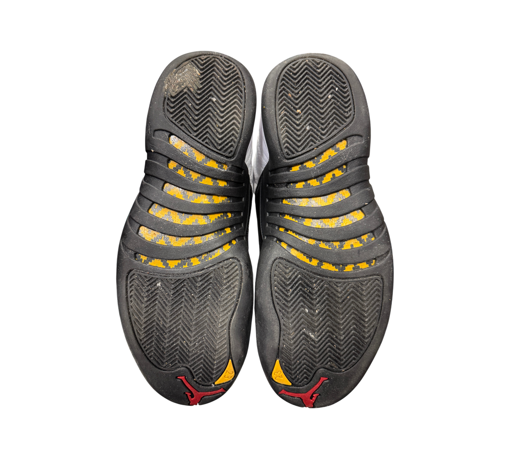 Used Jordan 12 Taxi sneakers from Genesis Boutique showing black and yellow herringbone outsoles with red Jumpman logo.