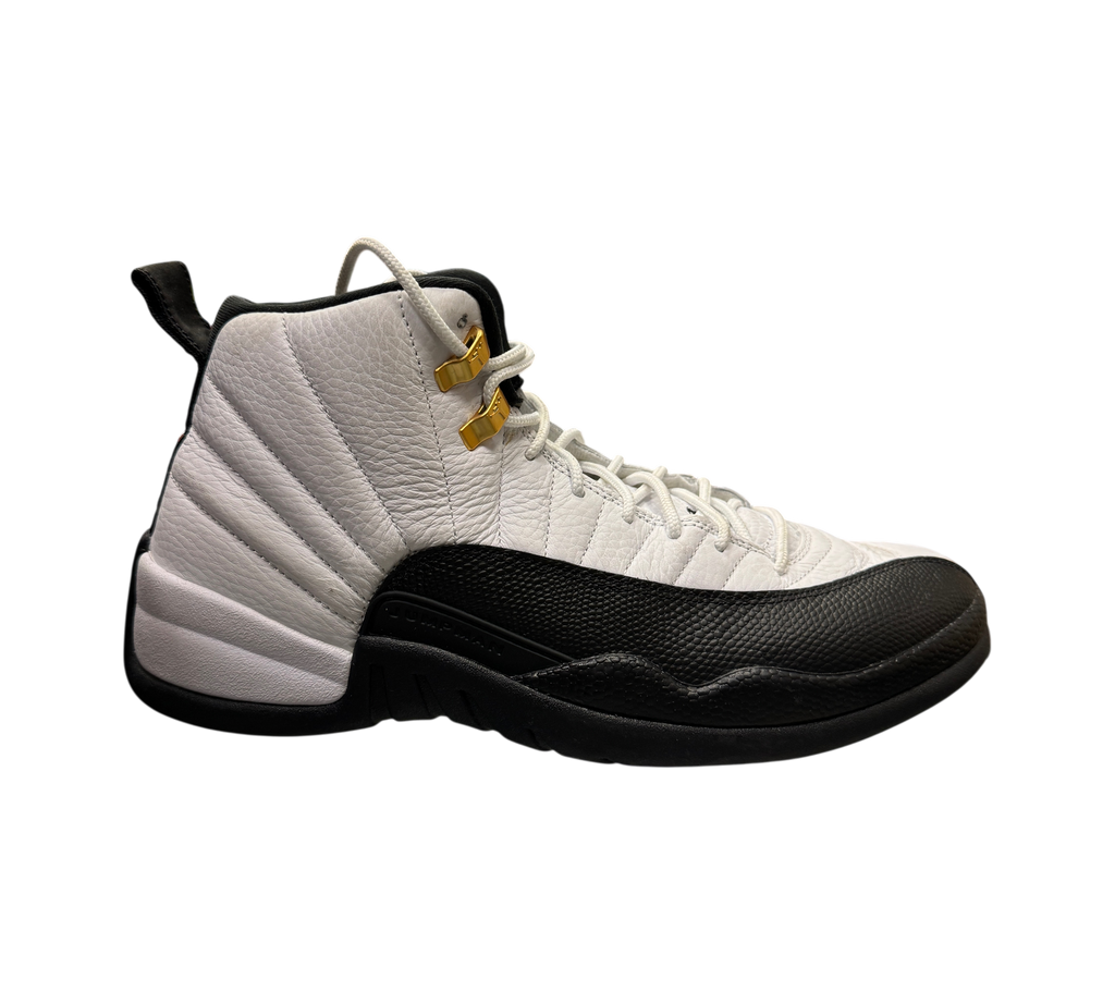 Genesis Boutique used Jordan 12 Taxi sneakers in white and black leather with gold eyelets on a glass display case.