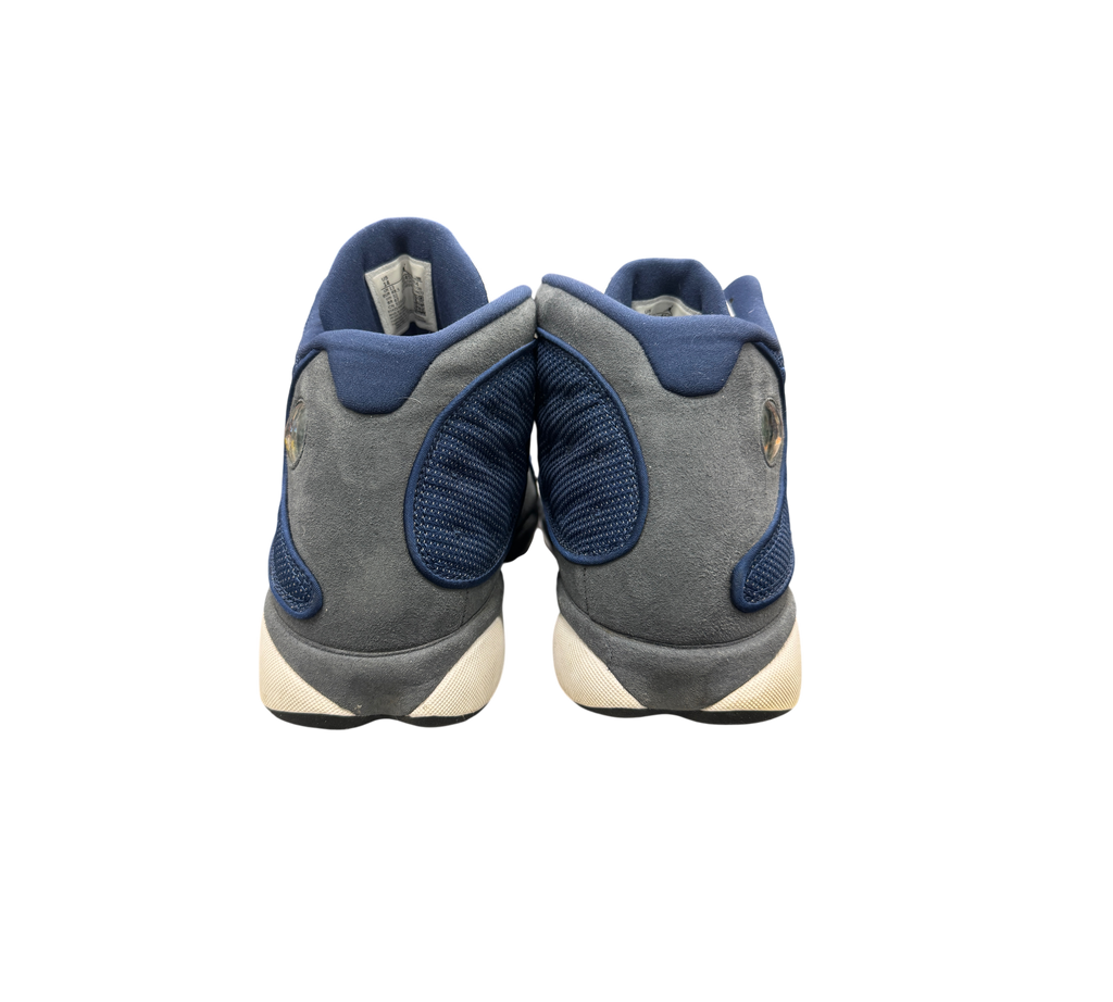Genesis Boutique Jordan 13 Flint sneakers showing the grey suede and blue mesh heel view with signature hologram logo.