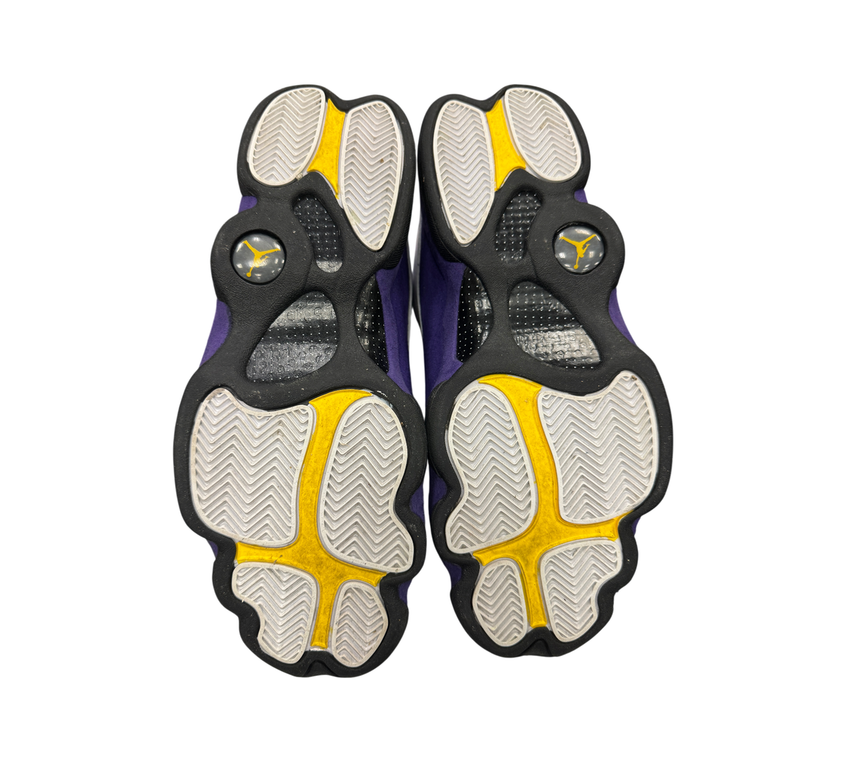 Genesis Boutique Jordan 13 Lakers sneakers showing the clean white, yellow, and purple patterned rubber outsoles.