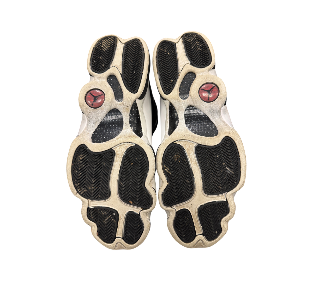 Genesis Boutique Jordan 13 Reverse He Got Game sneakers showing the black and white treaded outsoles with red logos.