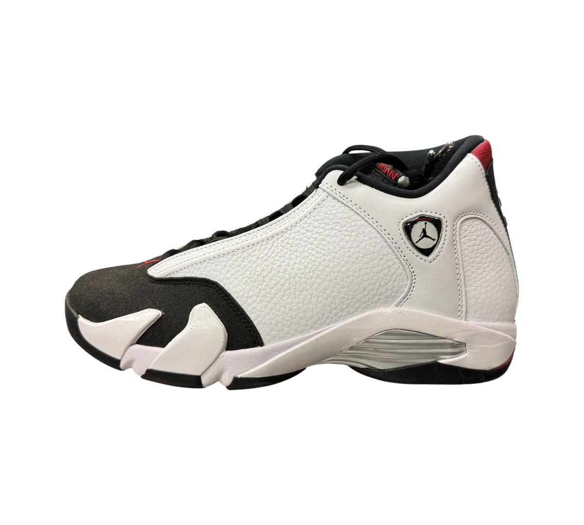Genesis Boutique Jordan 14 Black Toe sneakers in white and black leather with red accents on a glass display counter.