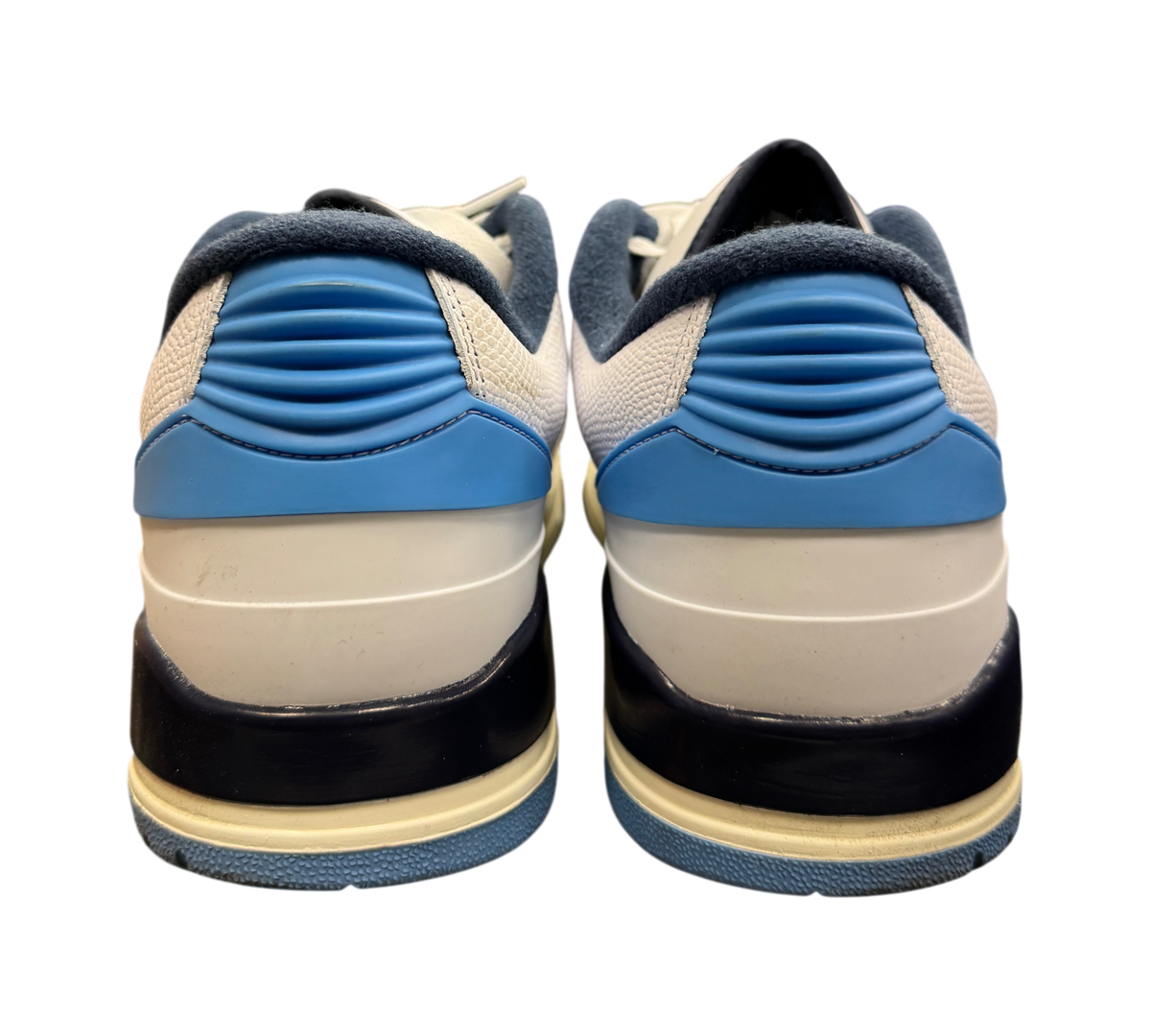 Genesis Boutique Jordan 2/3 UNC sneakers showing the white, blue, and navy heel design on a glass display case.