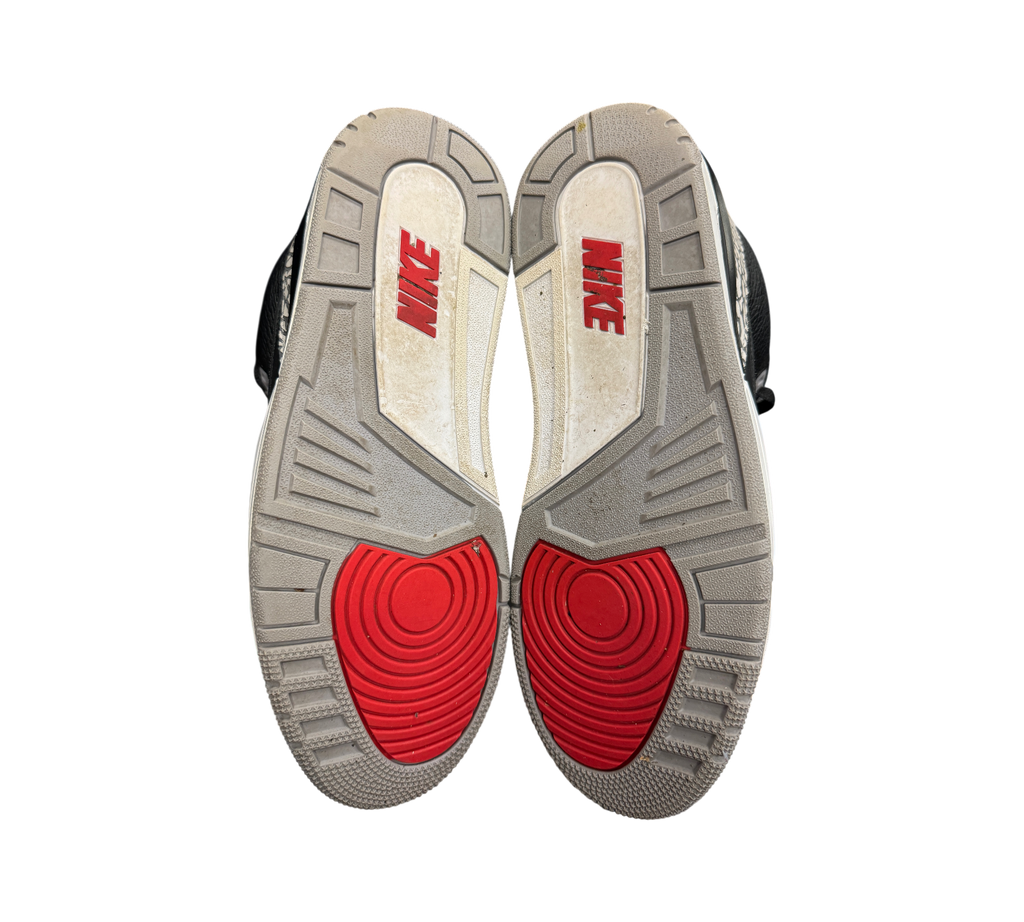 Outsoles of used Genesis Boutique Jordan 3 2018 Black Cement sneakers featuring red Nike branding and grey tread.
