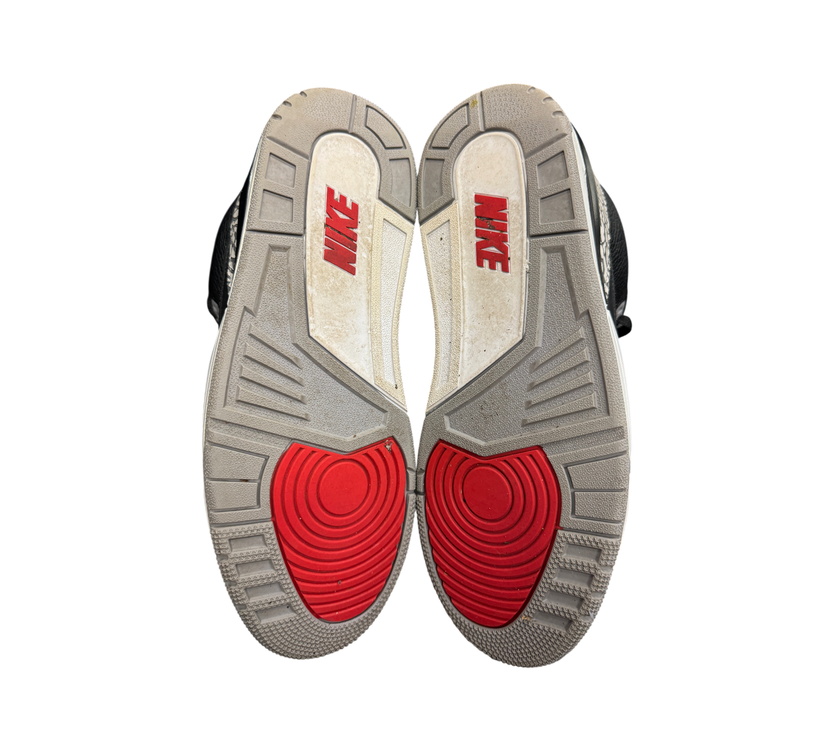 Outsoles of used Genesis Boutique Jordan 3 2018 Black Cement sneakers featuring red Nike branding and grey tread.