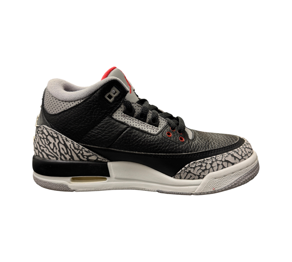 Genesis Boutique Jordan 3 GS Black Cement sneakers featuring iconic elephant print and red accents on a glass display