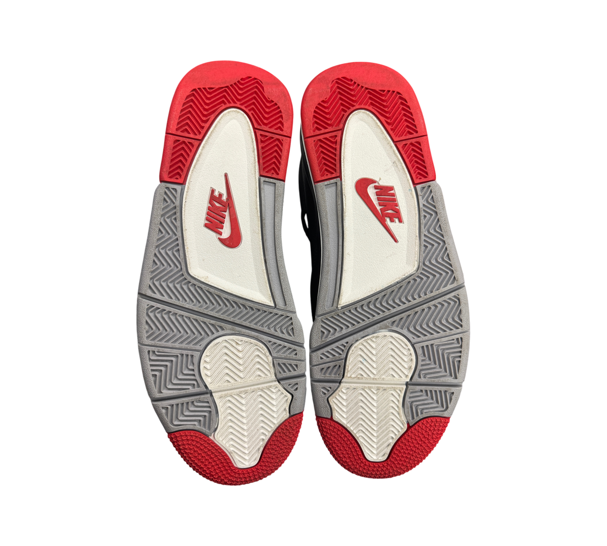Genesis Boutique Jordan 4 Bred Reimagined sneakers showing the red, grey, and white rubber outsoles with Nike branding.