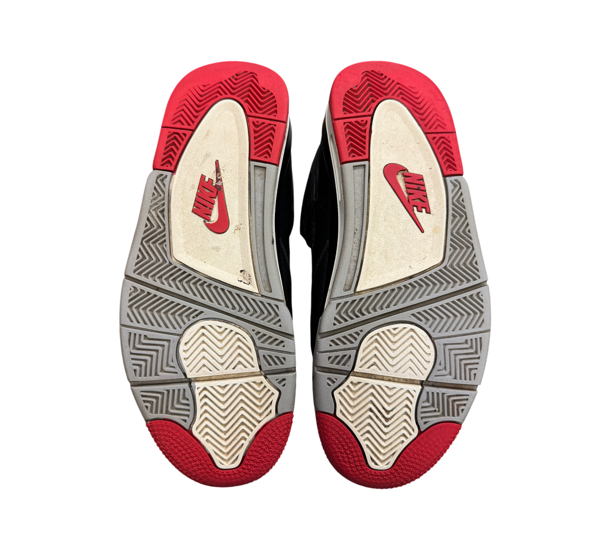 Genesis Boutique Jordan 4 Bred Reimagined sneakers showing the red, grey, and white rubber outsoles with Nike branding.