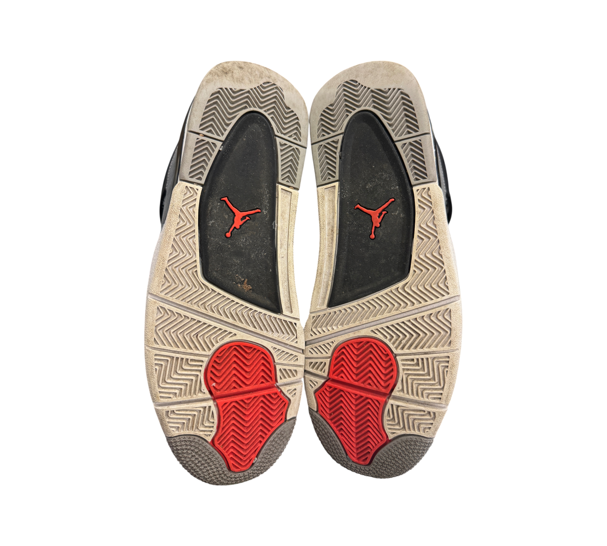 Genesis Boutique used Jordan 4 Infrared sneakers showing the worn grey and red rubber outsoles with Jumpman branding.