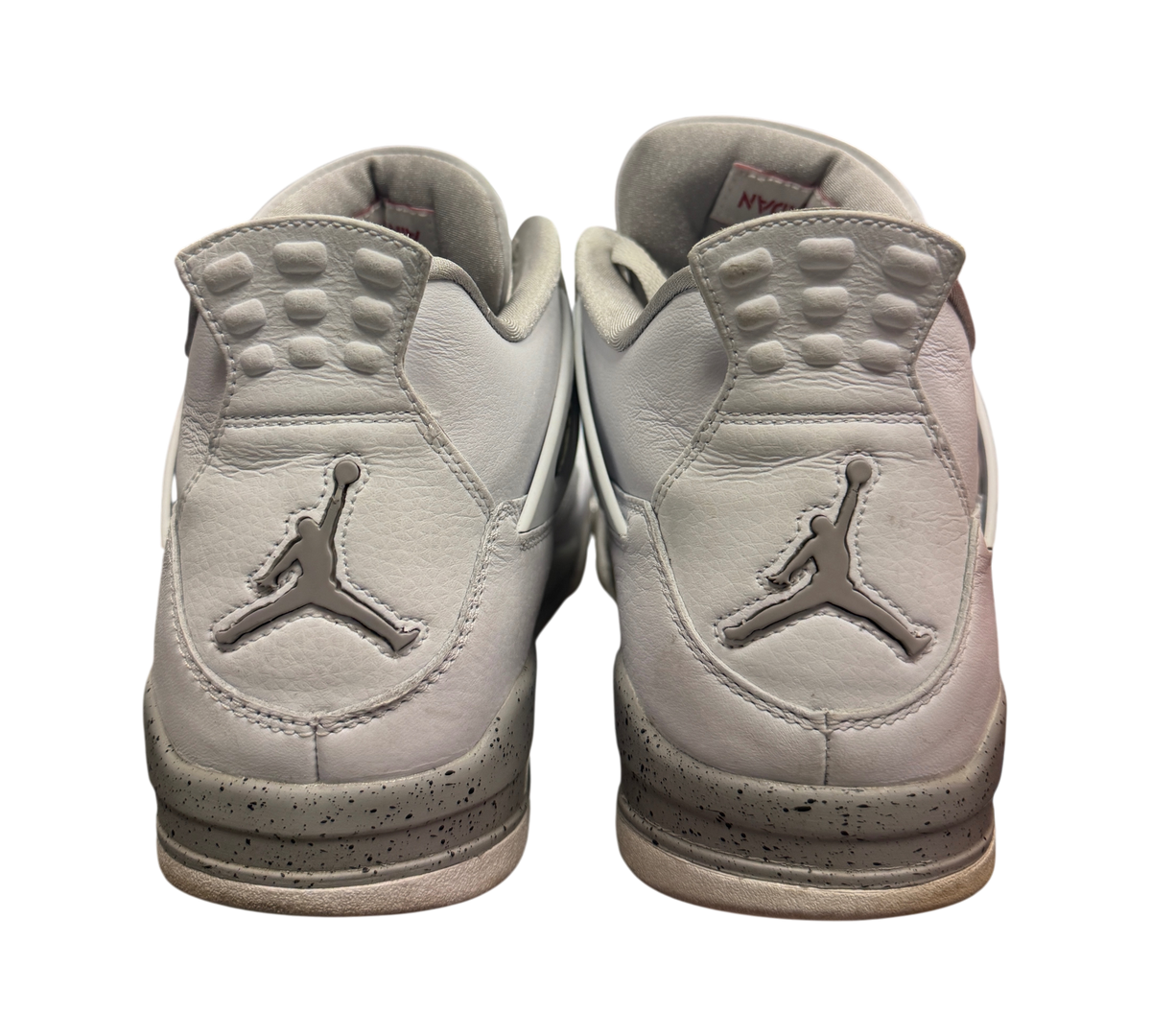 Genesis Boutique used Jordan 4 Oreo sneakers showing the white leather heels and grey speckled midsoles from behind.