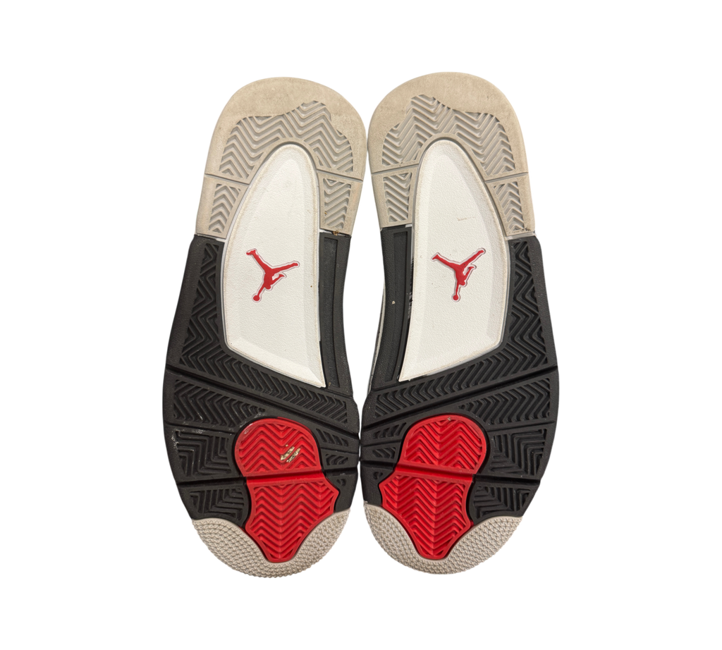 Genesis Boutique used Jordan 4 GS White Cement 2025 sneakers showing the black, white, and red rubber outsoles.