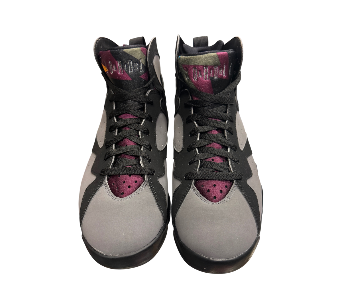 Genesis Boutique Jordan 7 Bordeaux sneakers in grey and black with purple accents on a glass display case