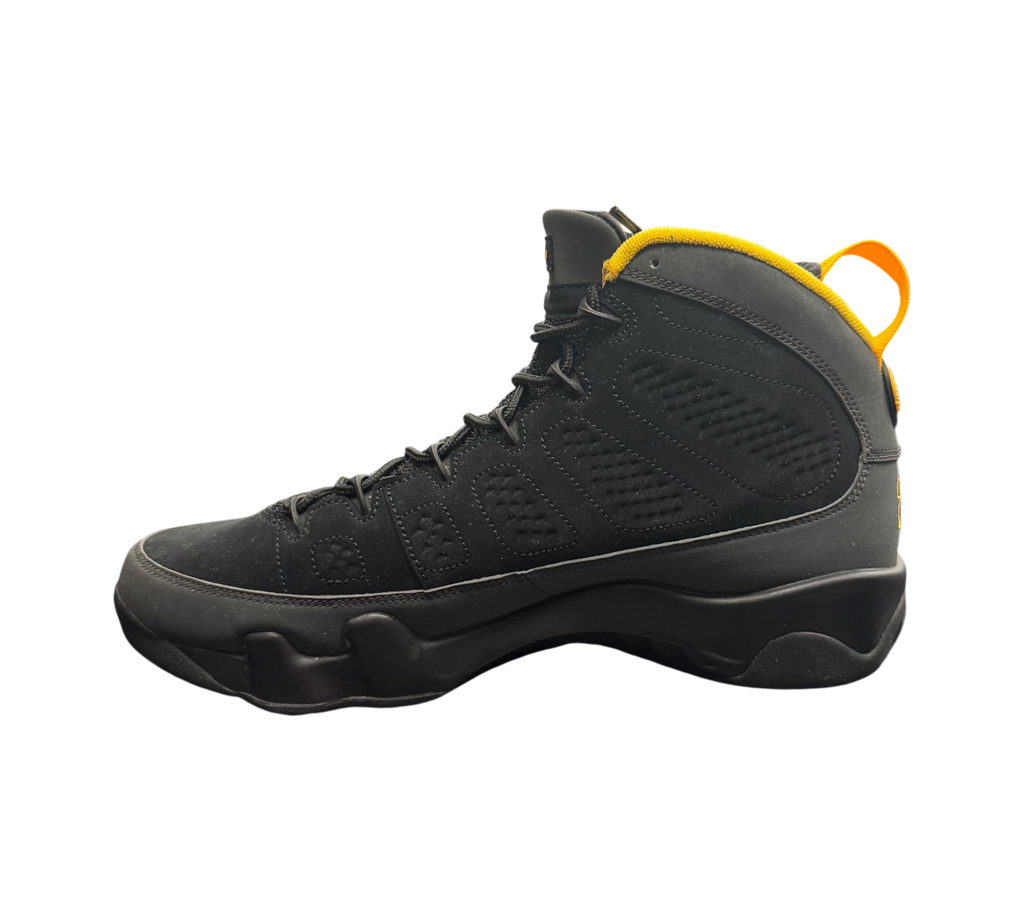 Genesis Boutique Jordan 9 Charcoal sneakers in black nubuck with yellow accents on the collar and heel pull tab.