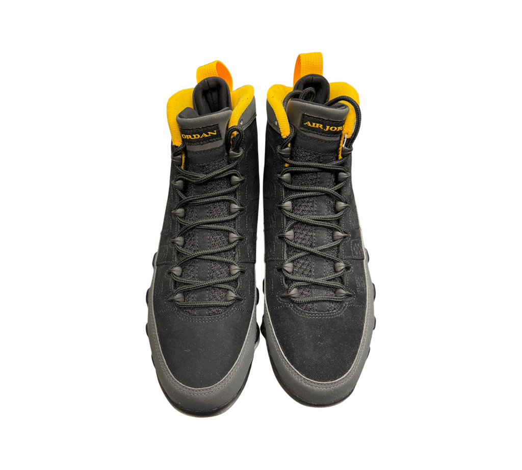 Genesis Boutique Jordan 9 Charcoal sneakers in black and grey nubuck with vibrant yellow accents on a glass display