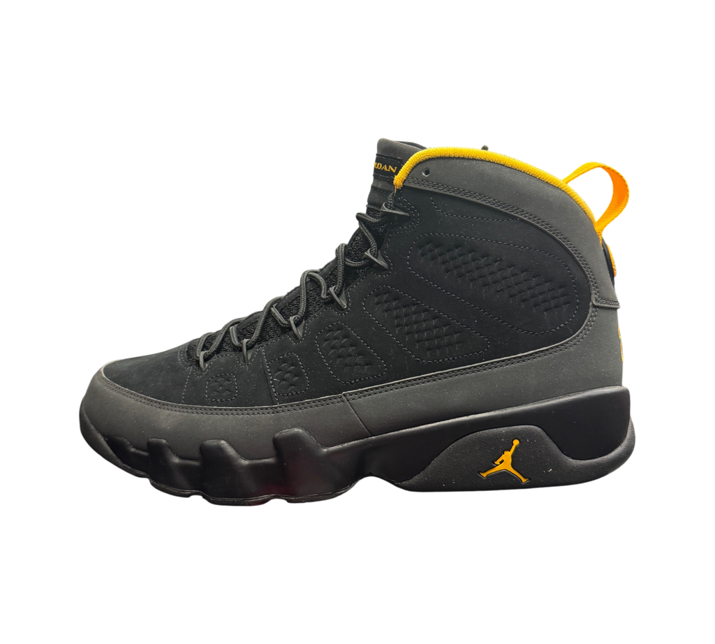 Genesis Boutique Jordan 9 Charcoal sneakers in black nubuck with yellow accents on a branded shoe box in a store