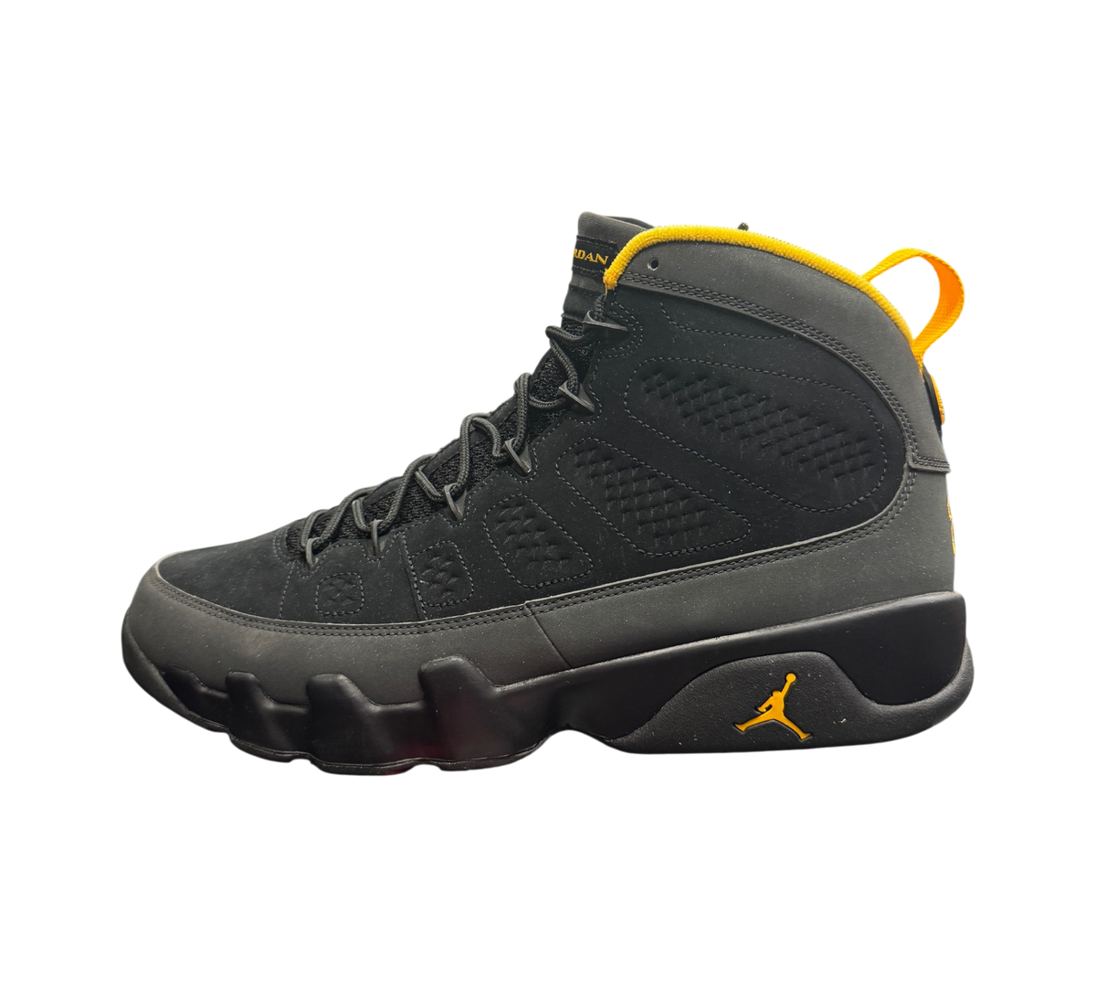 Genesis Boutique Jordan 9 Charcoal sneakers in black nubuck with yellow accents on a branded shoe box in a store