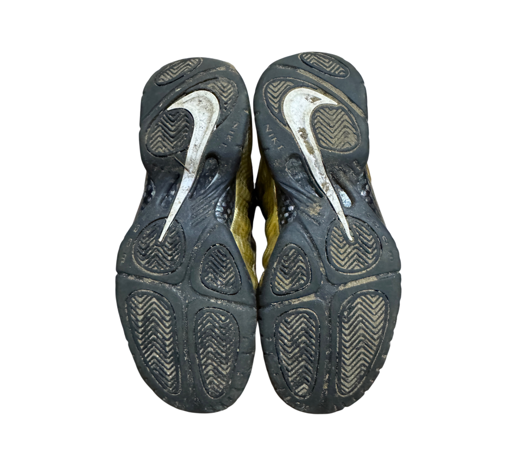 Genesis Boutique used Nike Air Foamposite 1 Gold sneakers showing worn black rubber outsoles with white Swoosh logos
