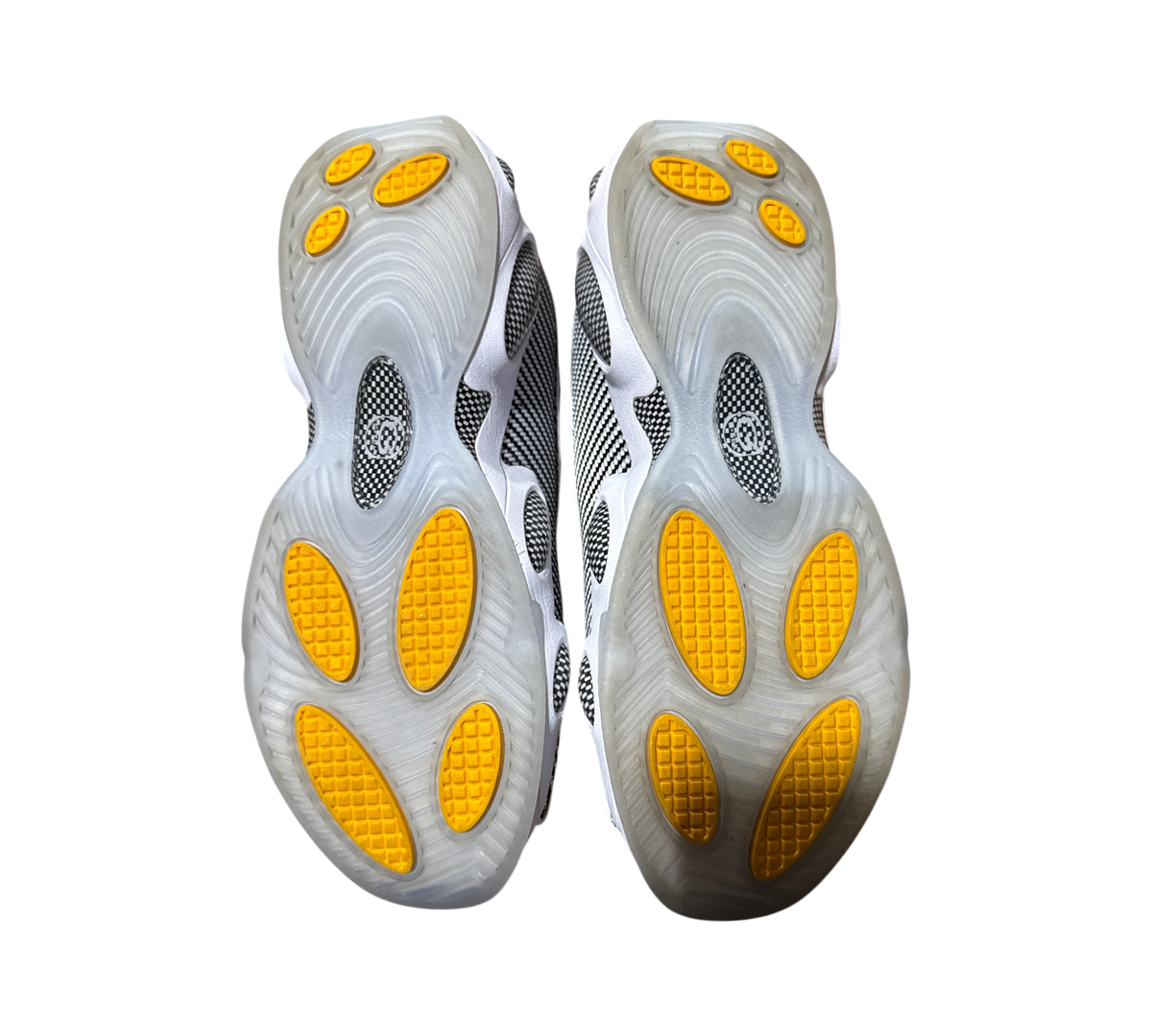 Genesis Boutique NOCTA x Nike Glide sneakers showing the black and white patterned outsoles with yellow traction pods